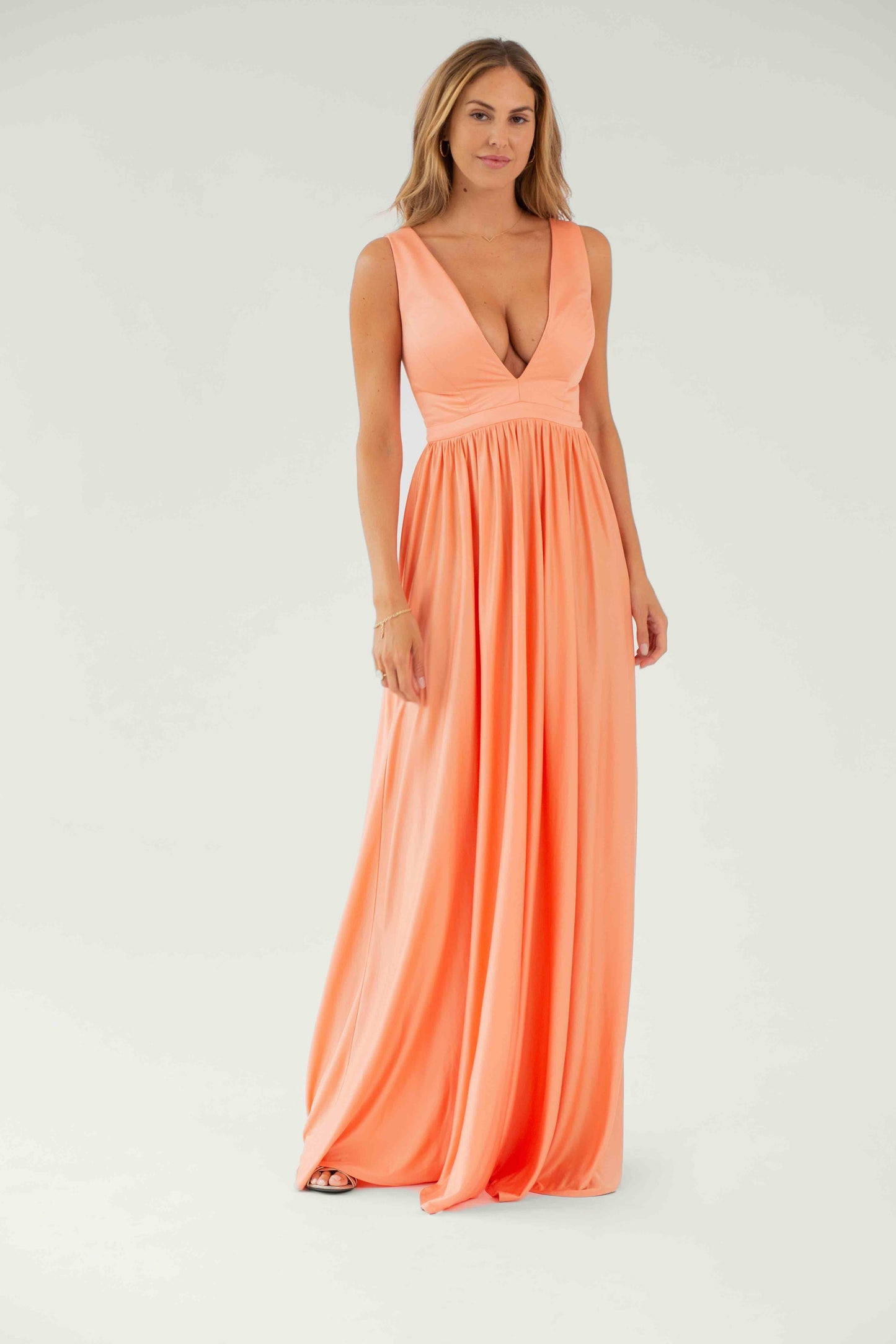 Model trägt das Malina Kleid in Shiny Peach – lang, mit tiefem V-Ausschnitt und Corsage mit Cups aus fließendem Modal
